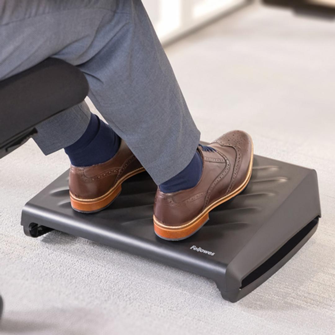 Repose-pieds réglable, 3 hauteurs et bascule Breyta FELLOWES - Pieds posés sur le repose-pieds Fellowes Breyta noir sous un bureau