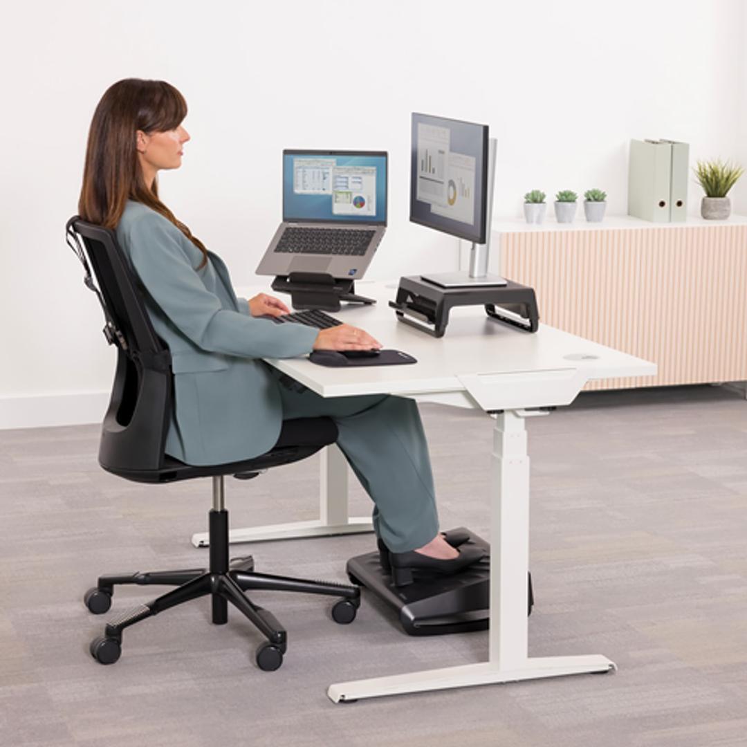 Repose-pieds réglable, 3 hauteurs et bascule Breyta FELLOWES - Repose-pieds Fellowes Breyta noir sous le bureau d'une utilisatrice assise