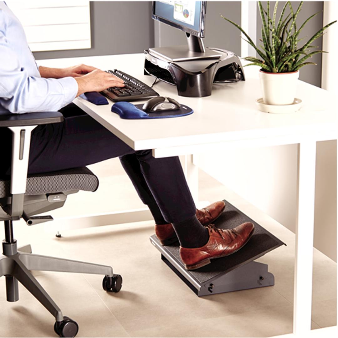 Repose-pieds en métal, grand plateau Professional Series métal FELLOWES - Repose-pieds métal Fellowes Professional Series, pieds posés dessus, sous un bureau