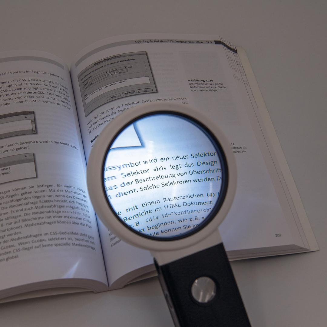 à main ou de table, x 2,5 et x 10 Loupe éclairée LED et UV à pied pliable WEDO - Loupe WEDO à pied pliable posée sur un livre