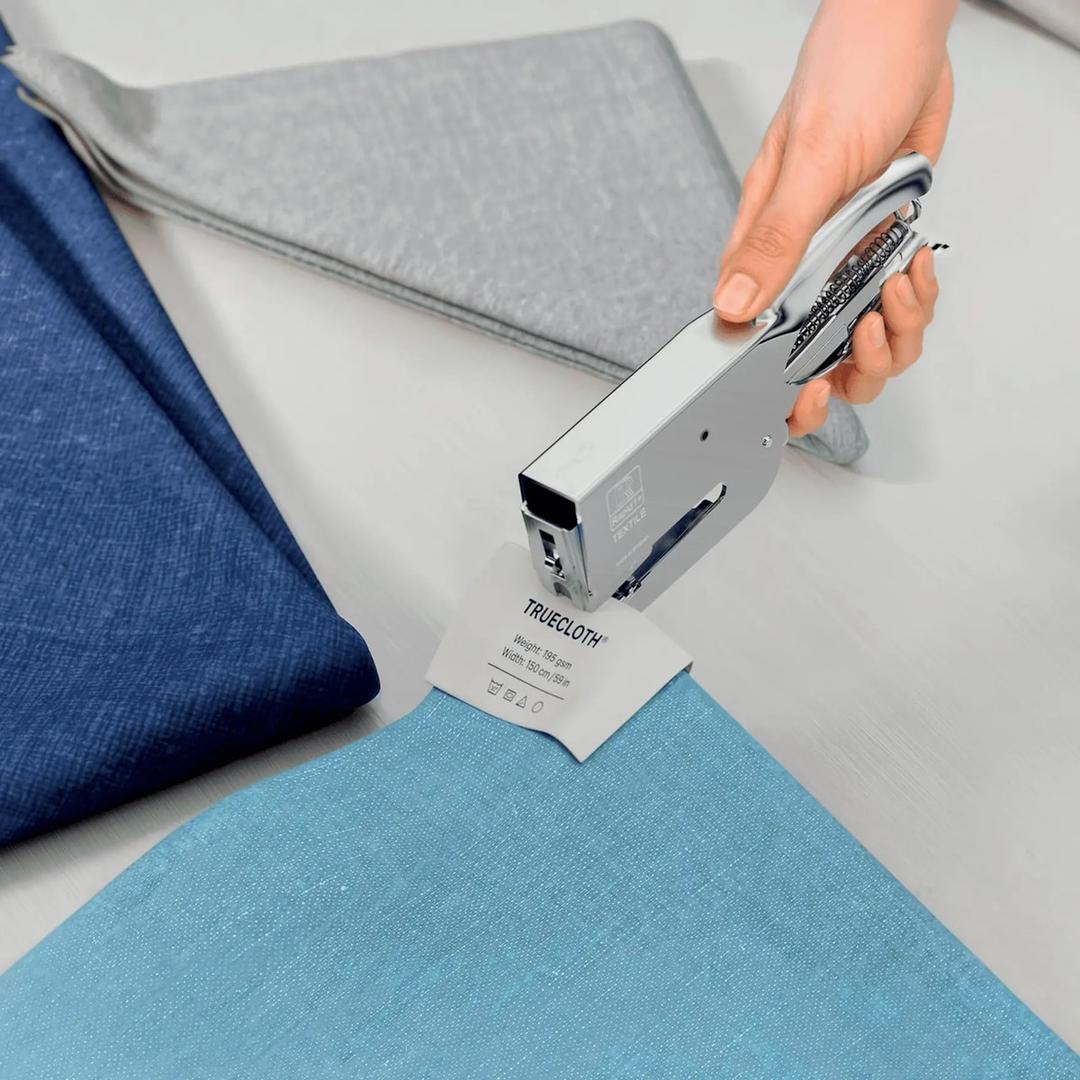 Étiquette fixée sur un tissu bleu avec la pince à agrafer les textiles Rapid Classic K1 Textile chromée.