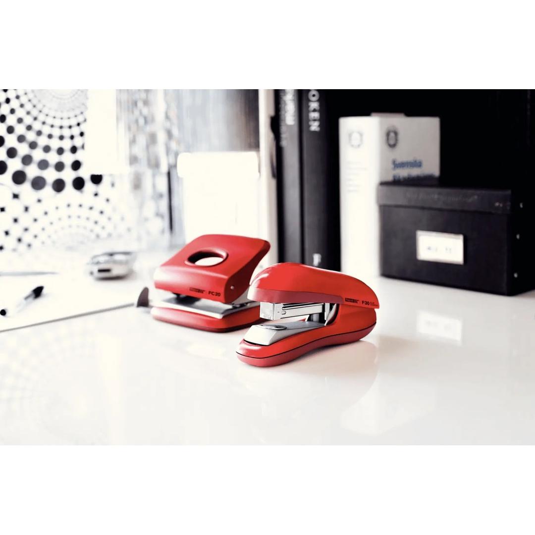 Agrafeuse de bureau à plat Rapid Fashion F30 rouge sur un bureau, avec un perforateur assorti.