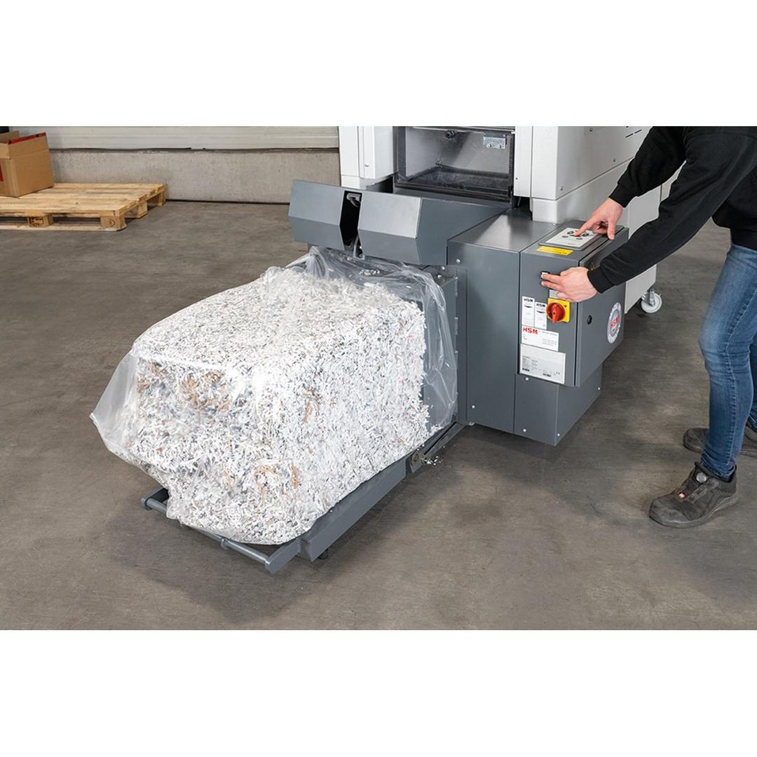 Combinaison destructeur-presse, coupe croisée P-4 Powerline SP 5080 3,9 x 40 mm HSM - Opérateur sortant une balle de papier compressé de la presse de la combinaison HSM Powerline SP 5080