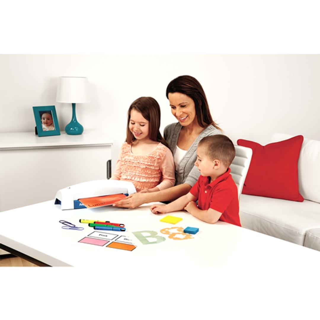 Plastifieuse à pochettes Fellowes Lunar+ A4 sur une table, une mère et ses enfants plastifient des dessins