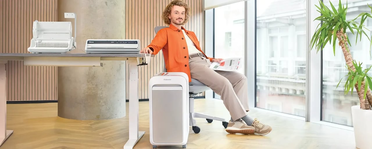 Bureau équipé Fellowes : perforelieuse et plastifieuse sur le plan de travail, destructeur de documents au pied du bureau