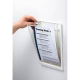Main qui ouvre la fenêtre de la plaque DURABLE CLICK SIGN A4 blanche pour changer la feuille