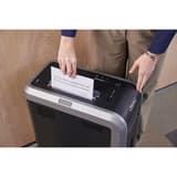 Gros plan sur l'insertion de feuilles de papier dans la fente d'alimentation d'un destructeur de documents Fellowes Powershred 125C  en environnement professionnel.