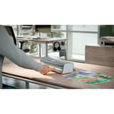 La plastifieuse à pochettes Leitz iLAM Office A4 posée sur un bureau, un document engagé dans la fente