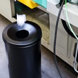 Corbeille anti-feu, couvercle étouffoir SAFE 60 litres DURABLE - Corbeille anti-feu DURABLE SAFE 60 litres noire, en usage, un papier jeté dans l'ouverture