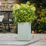 Colonne à plantes, décor béton BASALT'UP carré haut 50 cm vert amande POÉTIC - Colonne à plantes Poétic BASALT'UP carré haut 50 cm vert amande, en situation dans un jardin