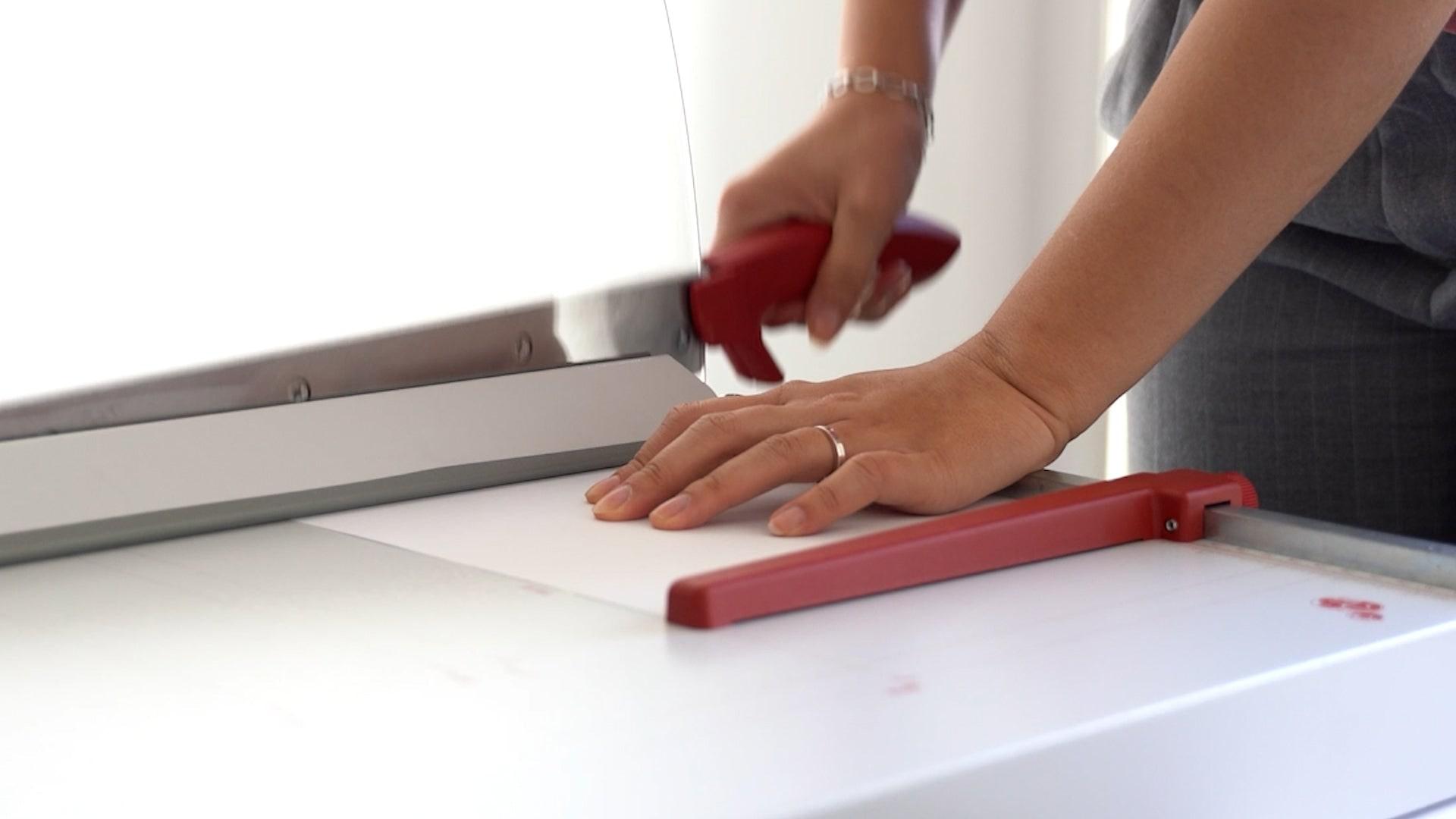 Mains qui coupent une feuille sur la cisaille IDEAL 1046