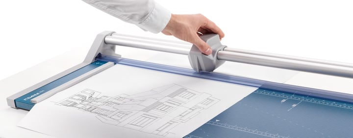 Rogneuse grand format Dahle coupant un plan, la main sur la tête de coupe